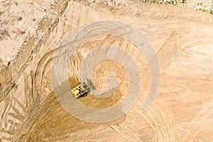 Aerial view of yellow industrial bulldozer working at construction site