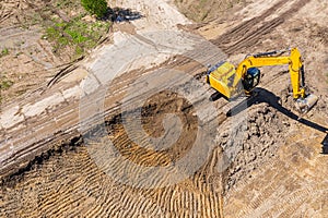 Aerial view of yellow industrial excavator working on construction site