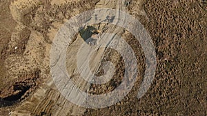 Aerial view of a yellow tractor that performs earthworks on a dirt road