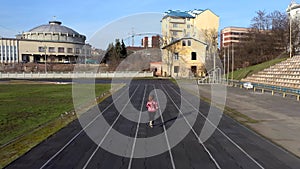 Aerial view of young athletic girl doing sports practice by running on sport