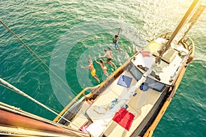 Aerial view of young friends jumping from sailing boat on sea