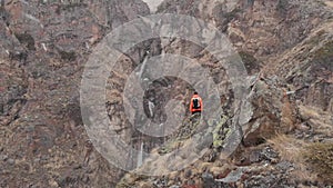 Aerial view of a young male photographer with a camera in his hands stands on a high rock in a gorge and photographs an