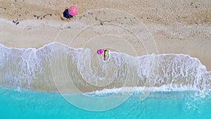 Aerial view of young woman with pink swim ring on the sandy beach