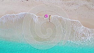 Aerial view of young woman with pink swim ring on the sandy beach