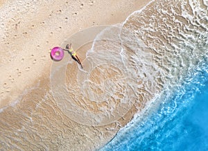 Aerial view of young woman with pink swim ring on the sandy beach