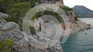 Aerial view of young woman on rock cliff against sea