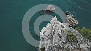 Aerial view of young woman on rock cliff against sea