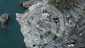 Aerial View of Young Woman on Rock Cliff Against Sea