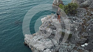 Aerial View of Young Woman on Rock Cliff Against Sea