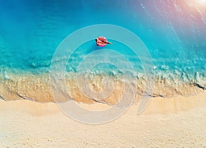 Aerial view of a young woman swimming with the donut swim ring