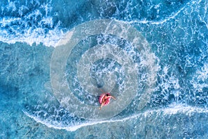Aerial view of a young woman swimming with the donut swim ring