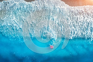 Aerial view of a young woman swimming with the donut swim ring