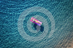 Aerial view of young woman swimming on the pink inflatable mattr