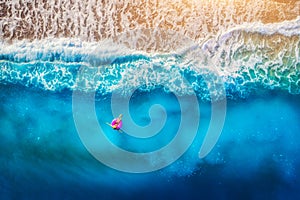 Aerial view of young woman swimming on the pink swim ring