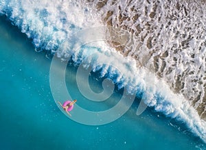 Aerial view of young woman swimming on the pink swim ring