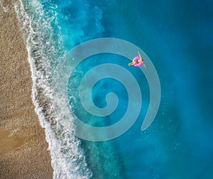 Aerial view of young woman swimming on the pink swim ring