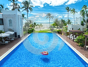 Aerial view of young woman on swimming ring in pool near ocean