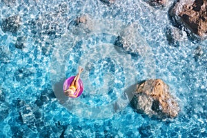 Aerial view of a young woman swimming with swim ring in blue sea