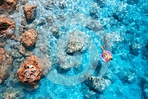 Aerial view of a young woman swimming with swim ring in blue sea