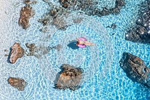 Aerial view of a young woman swimming with swim ring in blue sea