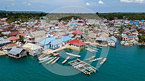 Aerial views of the village near the sea against the background of hills and forests along with many wooden boats lined