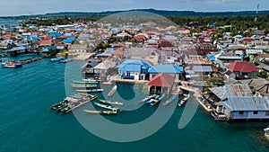 Aerial views of the village near the sea against the background of hills and forests along with many wooden boats lined