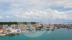 Aerial views of the village near the sea against the background of hills and forests along with many wooden boats lined