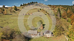 Aerial village at green mountain top. Autumn nobody nature landscape. Cottages at valley, forest