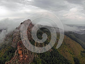 Aerial viw of fog among the mountain peaks. Bad weather and fog in the Siberian nature reserve Stolby.