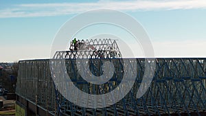 Aerial wide footage of an industrial roof, roofers installing a roof on an industrial building or warehouse.