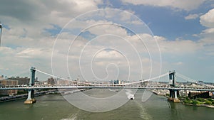 AERIAL wide footage over Brooklyn Bridge with American flag and East River view over Manhattan New York City Skyline