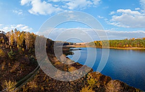 Aerial wide view of lake shore at sunrise in autumn. Meadows, orange grass, trees. Colorful landscape of river sunset. Horodok