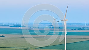 Aerial wind farm standing in farmland with green and light green crops