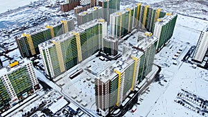 Aerial of winter cityscape with new resiential buildings and the ground covered by snow. Motion. Bird eye view o bright