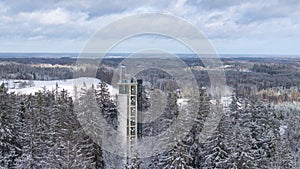 Aerial winter scenery of the Suur Munamagi hill with a watchtower and Estonian flag flying