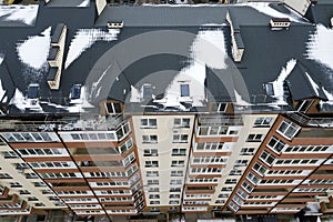 Aerial winter top view of tall apartment building, brick chimneys, tiled roof. Urban infrastructure, view from above