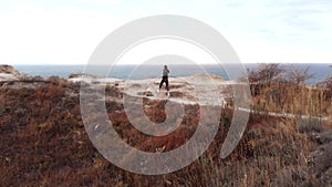 Aerial. A woman jogs on the coast at dusk. Sport on top of the mountain