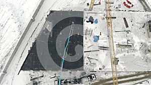 Aerial Work of a building crane, a view from above. Cement filling with a special crane. Winter construction