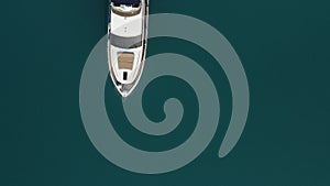 Aerial yacht on calm sea. Luxury cruise trip. View from above of white boat on deep blue water. Aerial top down view of