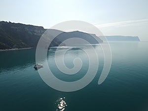 Aerial yacht on calm sea. Luxury cruise trip. View from above of white boat on deep blue water. Aerial top down view of