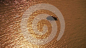 Aerial yacht on calm sea. Luxury cruise trip. View from above of white boat with golden bokeh lights from sun on calm