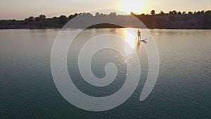 Aerial: young girl boarding SUP