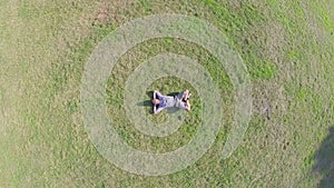 Aerial, young positive man lying on ground hands behind head