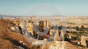 Aerial zoom out on amazing big sunny rock to reveal incredible clear sunrise desert panorama background with blue sky.