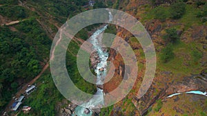 Aerial zoom out backwards view Chyamche waterfall by village house settlement.Annapurna circuit trek. Way to Manang
