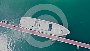 Aerial zoom out drone shot of luxury yacht moored by pier in dock port