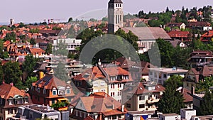 Aerial zoomed footage of town development in residential urban neighbourhood. Tilt up reveal of church with tower clock