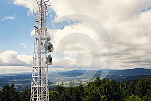 Aerials and transmitters on telecommunication tower with mountains in background