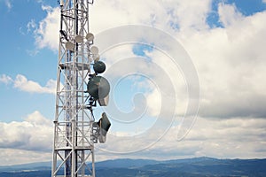 Aerials and transmitters on telecommunication tower with mountains in background