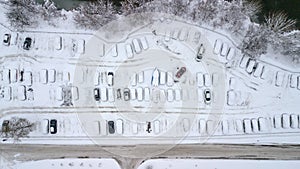 Aerila view of snow-covered cars stand in the parking lot on a winter day